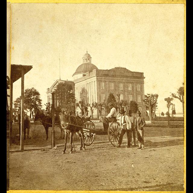 . In the background stand the Old Capitol, with the side of the building and the domed roof most visible