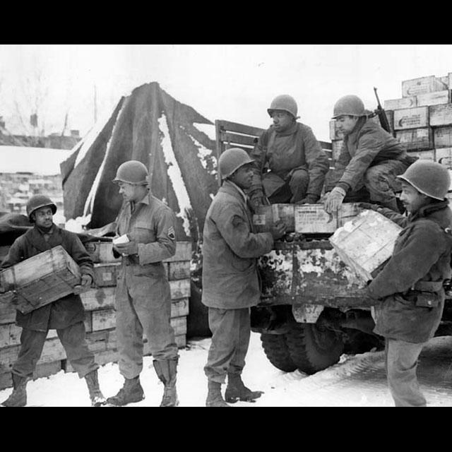 A black and white photograph of six Red Ball Express soldiers unloading a truck of supplies