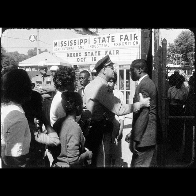 Black demonstrators standing outside of the entrance to the Mississippi State Fair